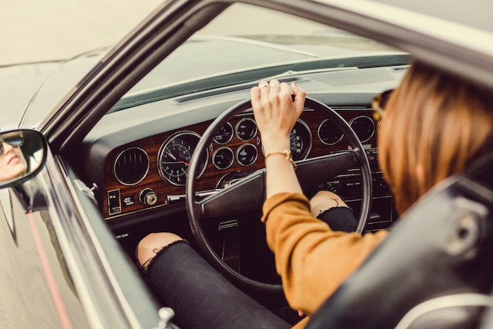 Jeune femme au volant d'une voiture de collection