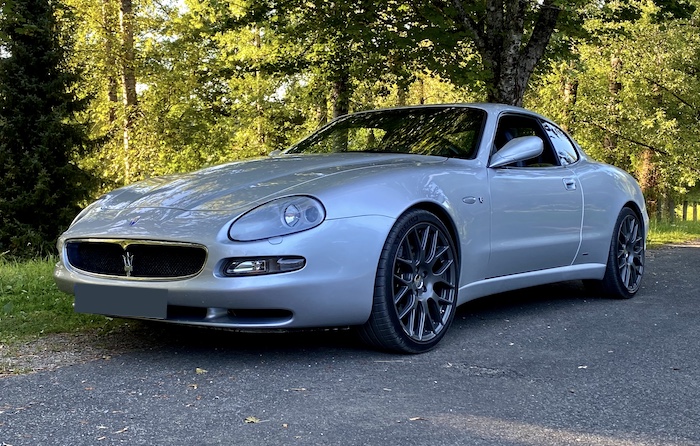 Maserati Coupé Cambiocorsa argenté de 3/4 face devant un bois