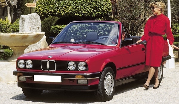 BMW E30 cabriolet rouge décapotable dans un jardin