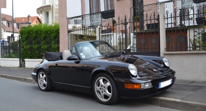 Porsche 964 cabriolet noire de 3/4 face sur un trottoir