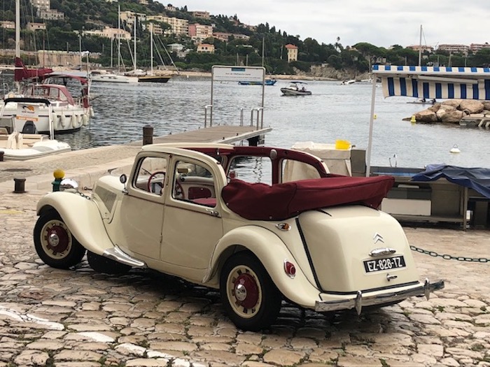 Citroën Traction découvrable beige avec intérieur rouge sur un port méditerranéen