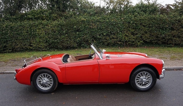 MG MGA rouge de profil avec intérieur marron sur une route humide
