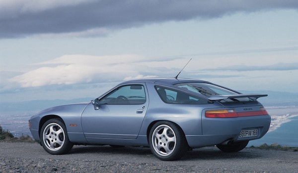 Porsche 928 GTS grise de profil/arrière sous un ciel nuageux