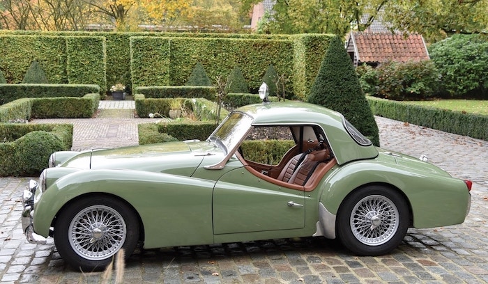 Triumph TR3 vert clair avec son hard-top et sièges couleur camel sur une route pavée