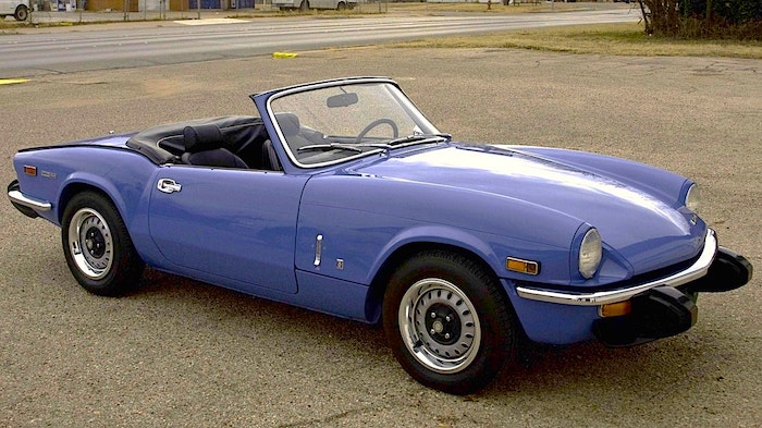 Triumph Spitfire décapotable mauve de 3/4 face sur un parking