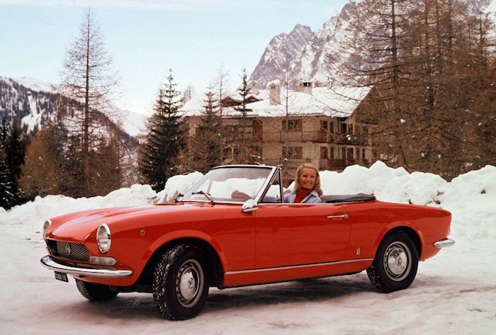Fiat 124 spyder de profile dans la neige et sa conductrice