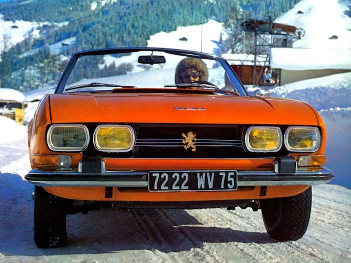 Peugeot 504 cabriolet orange de face en montagne dans la neige