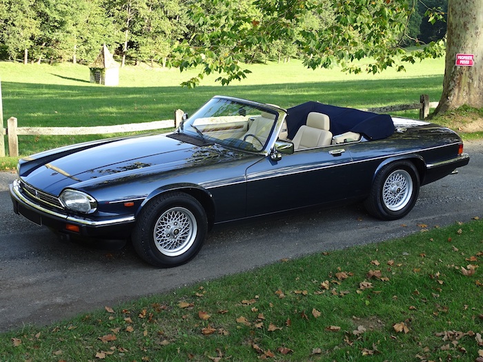 Jaguar XJS V12 cabriolet bleu métallisé et intérieur beige sur une route de campagne