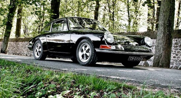 Porsche 912 noire sur une route boisée