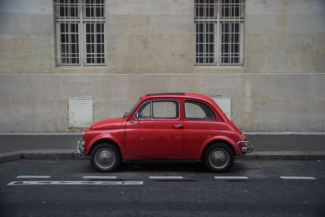 Fiat 500 classique rouge garée dans une rue parisienne