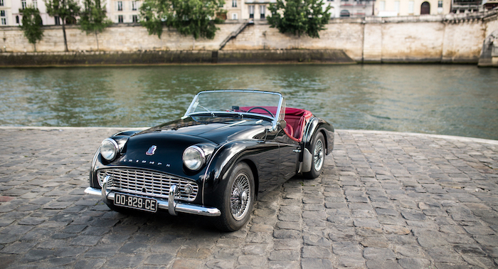 Triumph TR3 noire avec intérieur rouge sur les berges parisiennes