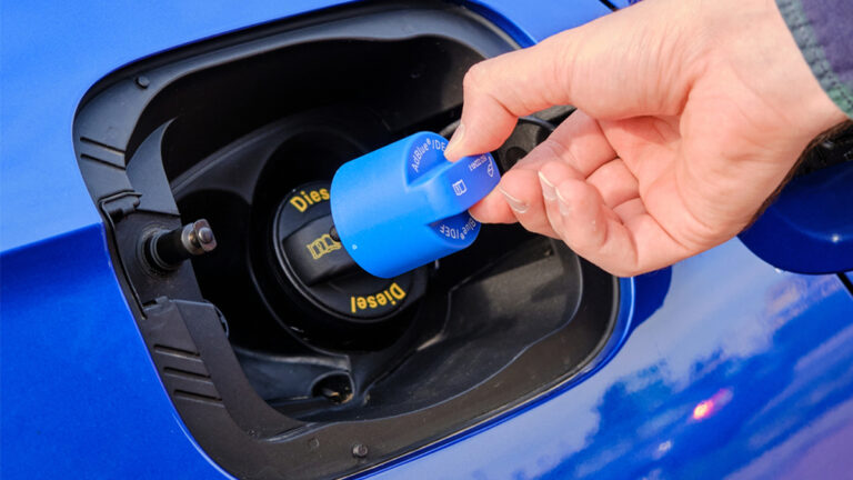 main qui retire un bouchon d'ad blue sur une voiture